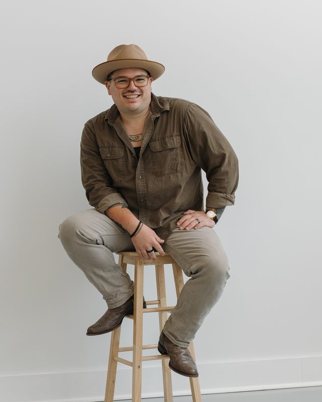 Keegan Sullivan, founder of Handled, sitting on a wooden stool, smiling.